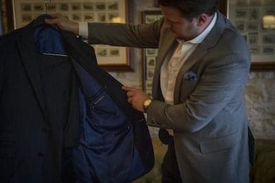 Man holding navy suit showing the navy lining.