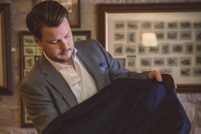 Man dressed in a suit holding a bespoke suit on a hanger